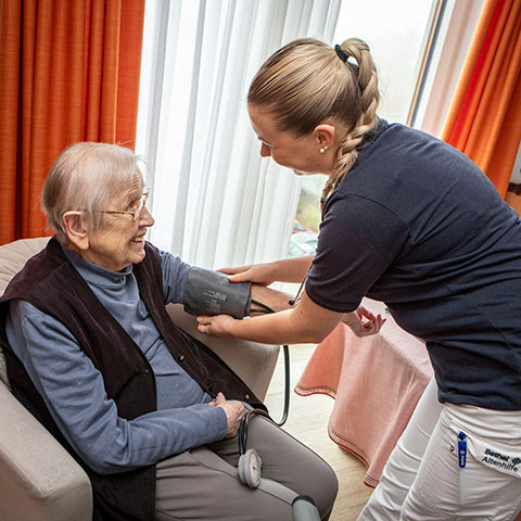 Pflegekraft misst den Bludruck einer Bewohnerin des Pflegezentrums Haus Hannah